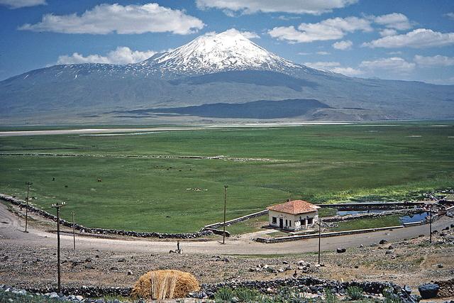 Snow-capped Mount Ararat rising above a green plain on the Turkish side